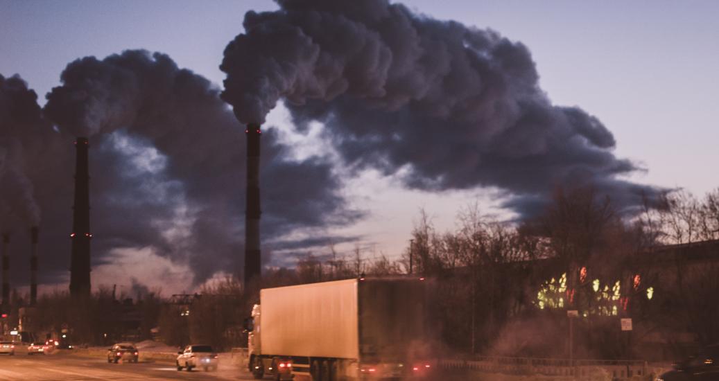 Véhicules roulant devant des cheminées d'usine