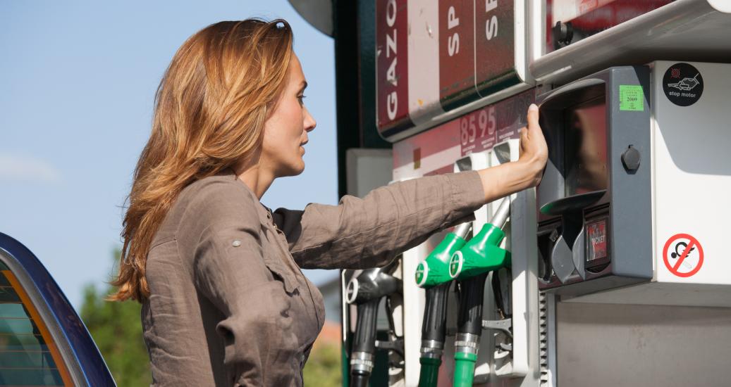 Femme devant station carburant