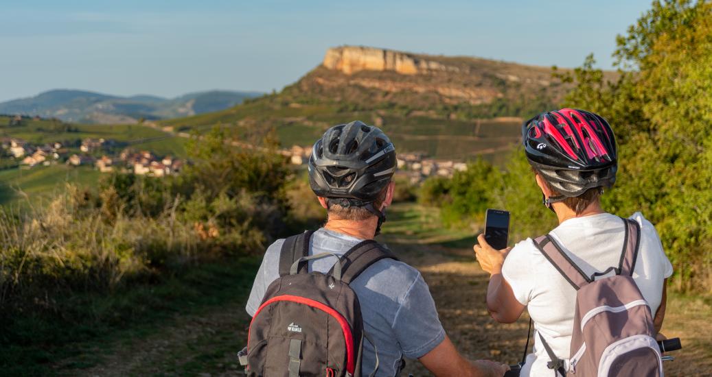 Deux cyclistes regardent leur téléphone devant un paysage montagneux