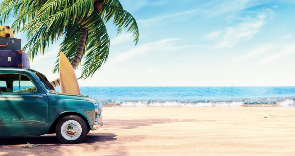 Une voiture chargée de bagages sur la plage, sous un palmier