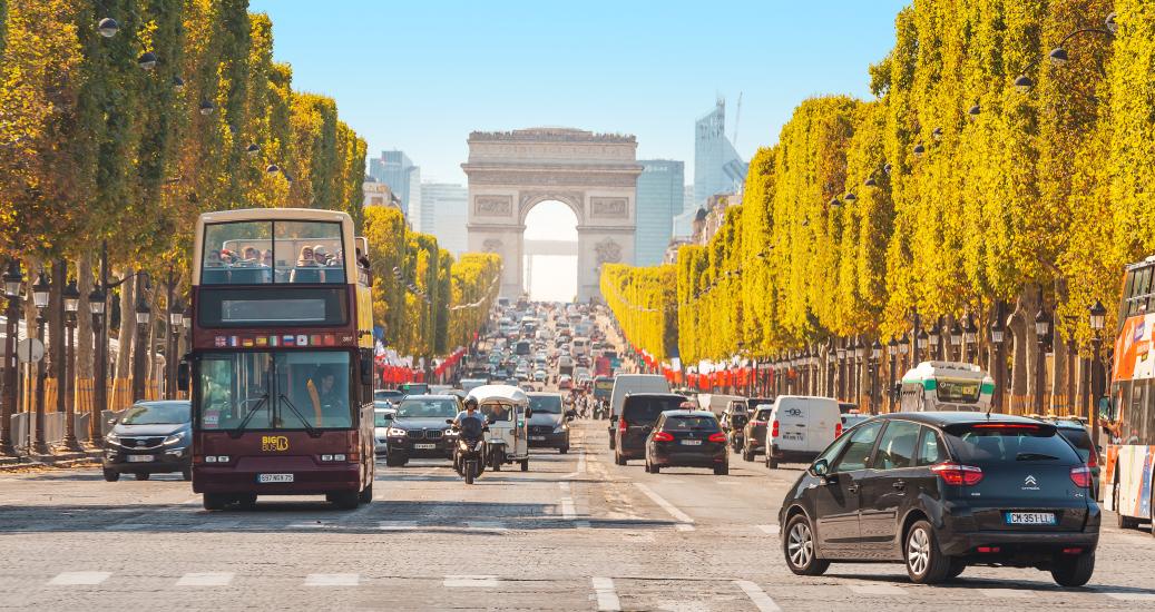 29 July 2019, Paris, France: Buses and cars drive along Avenue Champs Elysees with the Arc de Triomphe in the background