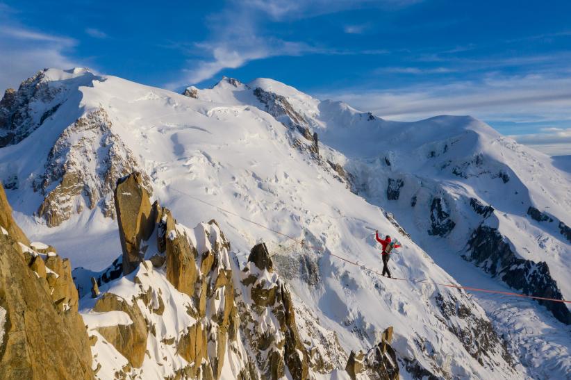 Nathan Paulin en équilibre sur un câble à l'Aiguille du Midi avec la flamme olympique