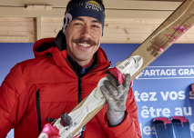 Animateur en gilet rouge portant des skis à la main